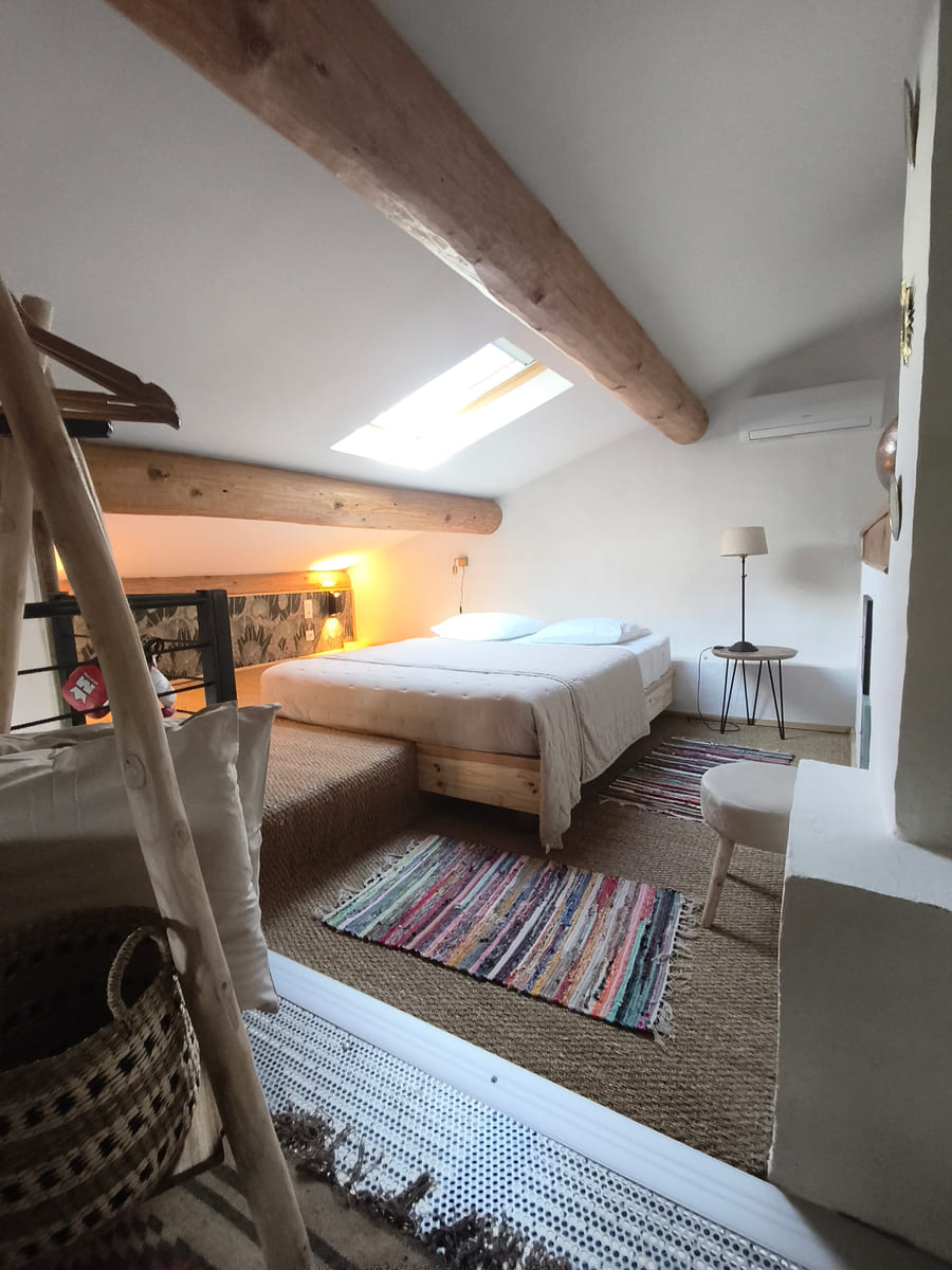 La chambre vue depuis l'escalier de la mezzanine, tapis colorés et sol en jonc de mer